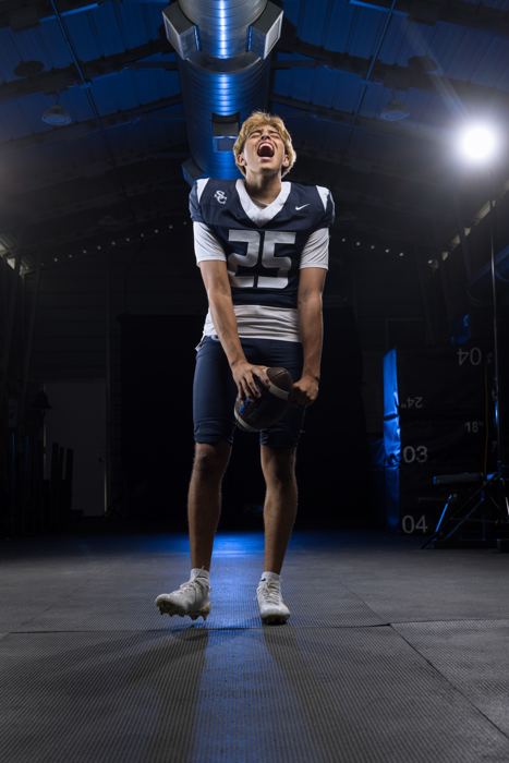 Davide Morales yelling with football in hand under blue arena lights